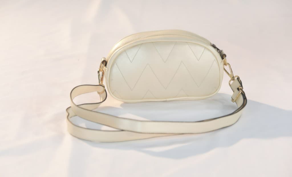 Cream chevron-quilted dome crossbody bag with gold-tone hardware