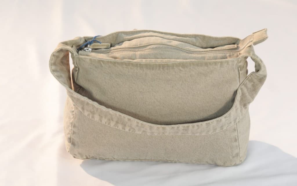 Khaki canvas shoulder bag with multiple zippered compartments
