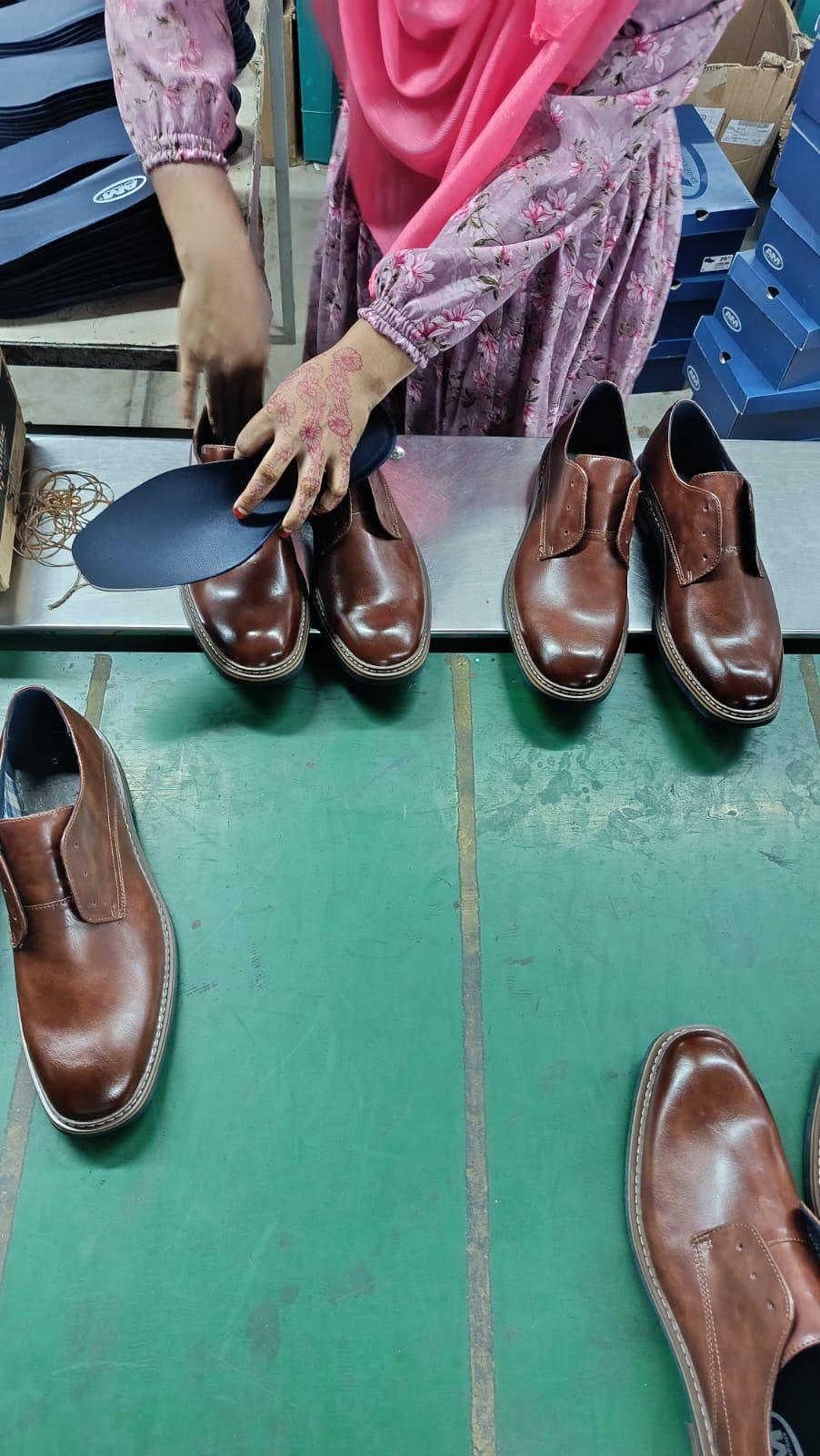 Insole fitting into brown leather dress shoes during footwear production