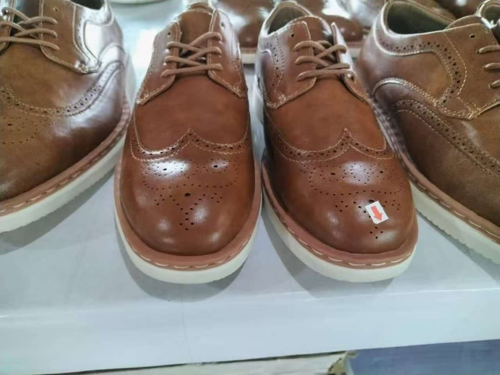 Brown leather brogues marked for quality inspection on the production line